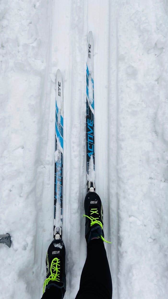 Services A high-angle shot of skis and boots on a snowy trail, capturing the essence of winter sports.